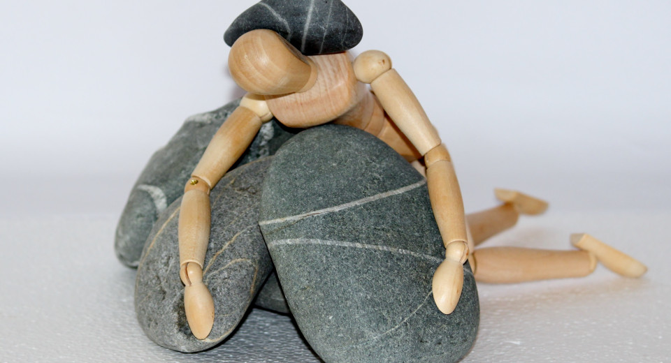 foto van houten figuurtje en stenen die stress uitbeelden